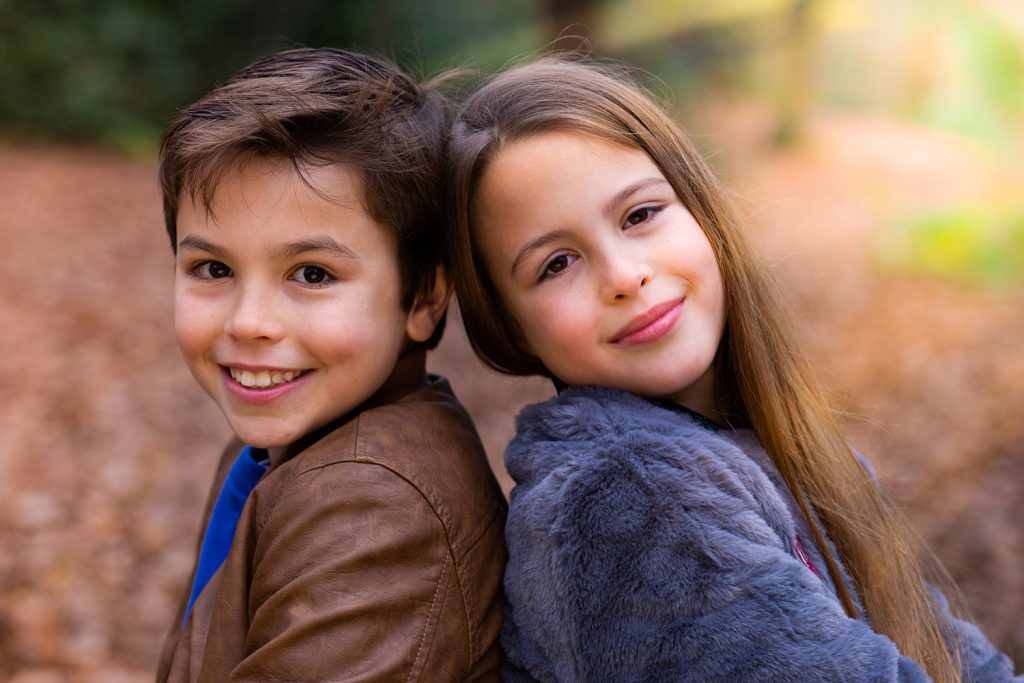 Brother and sister sitting side by side in the woods