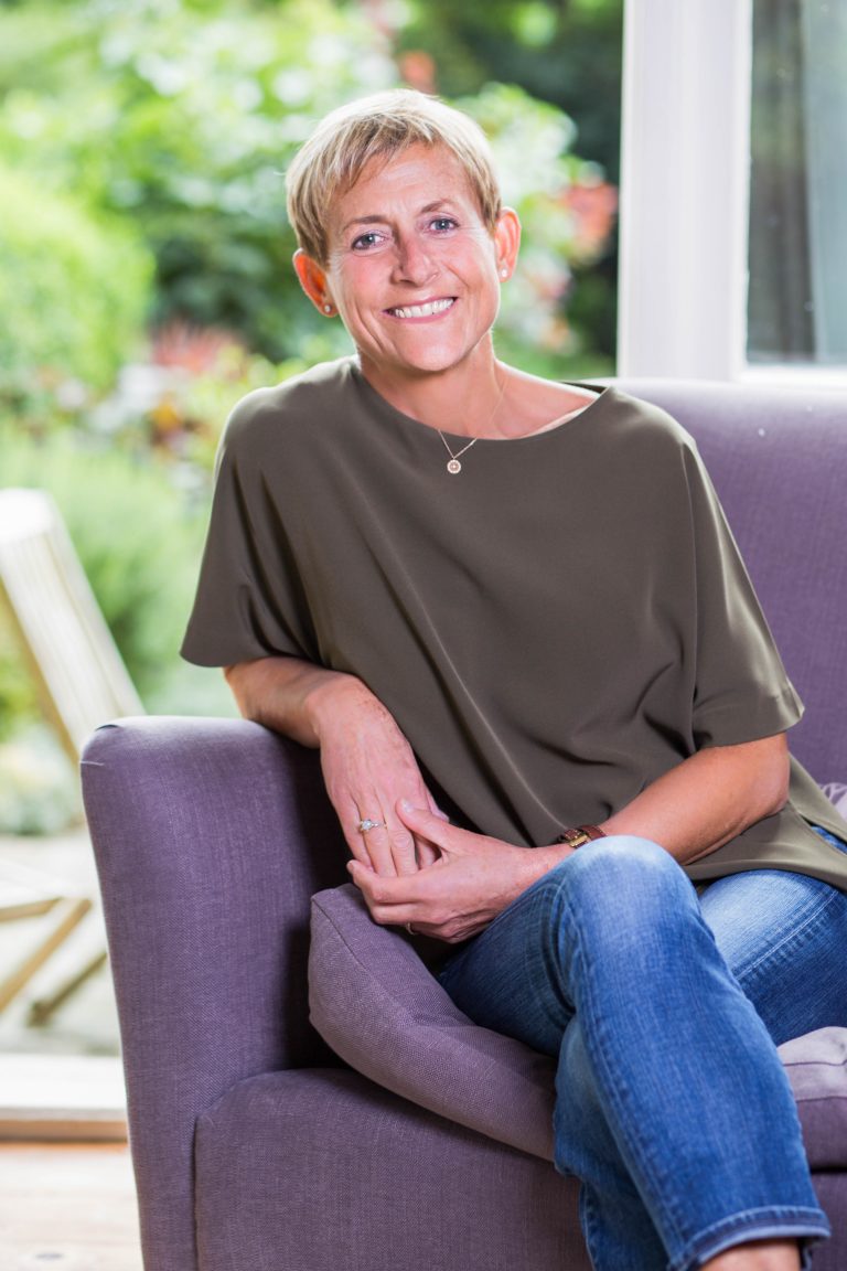 friendly woman in jeans sitting on purple sofa