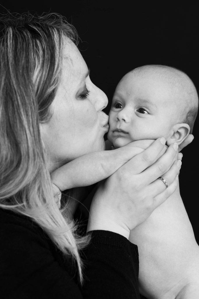 black and white photo of mother kissing her baby