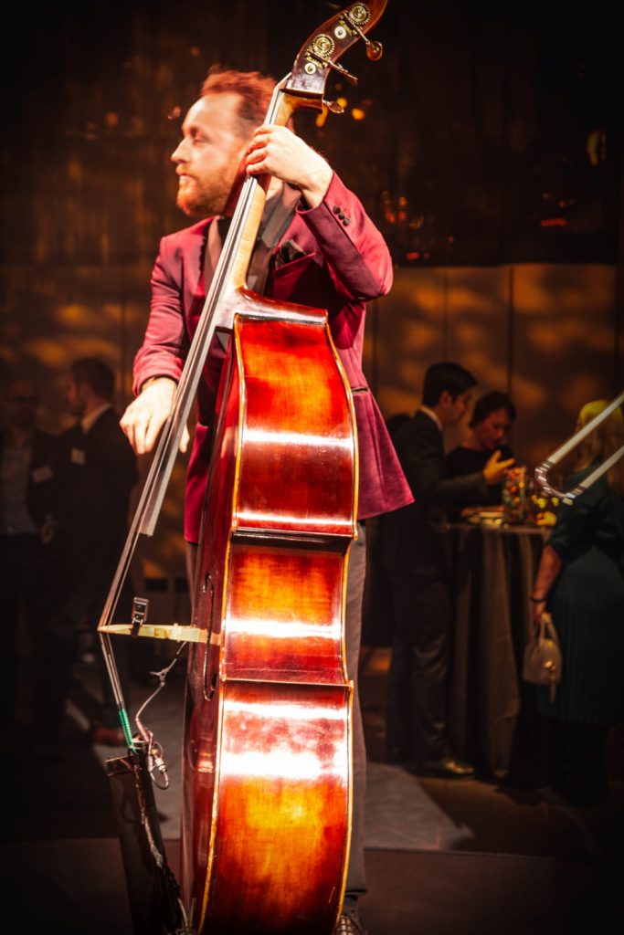 Double bass player in red velvet jacket playing in a band